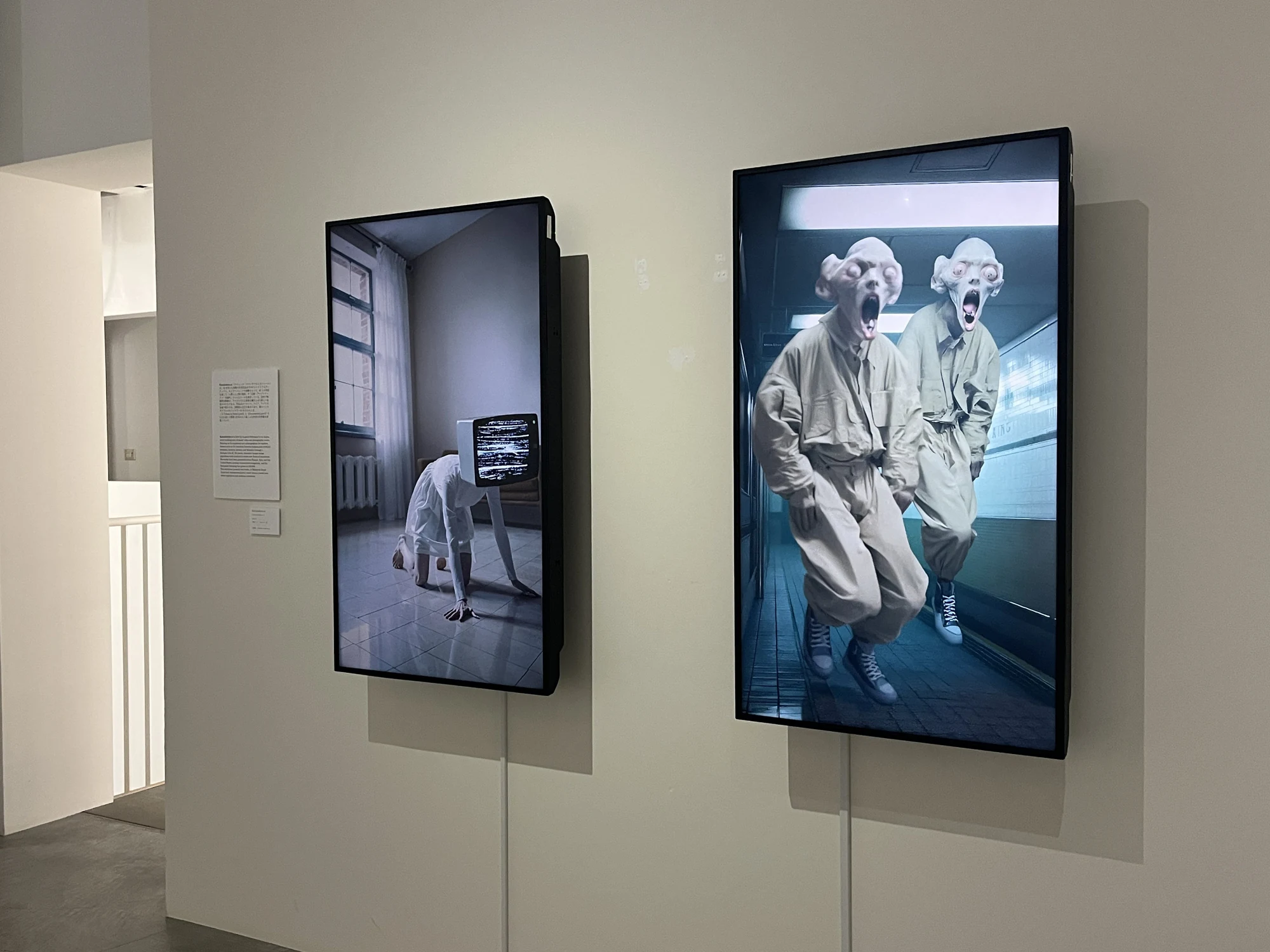 Two vertical screens showing Katsukokoiso.ai video artworks on a wall at Karuizawa New Art Museum.